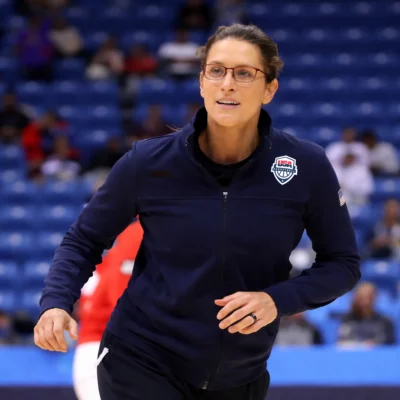 Woman coach in navy sports jacket training on basketball court
